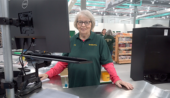 Cashier smiling for the camera at the front checkout