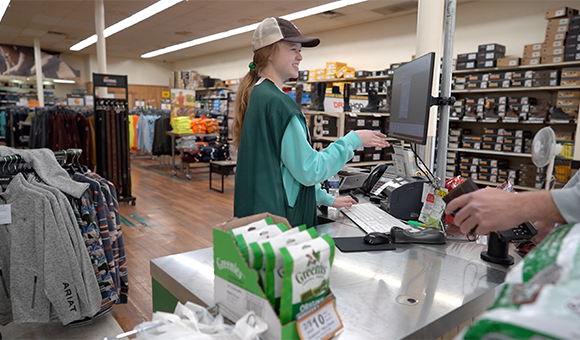 cashier smiling while helping a customer checkout