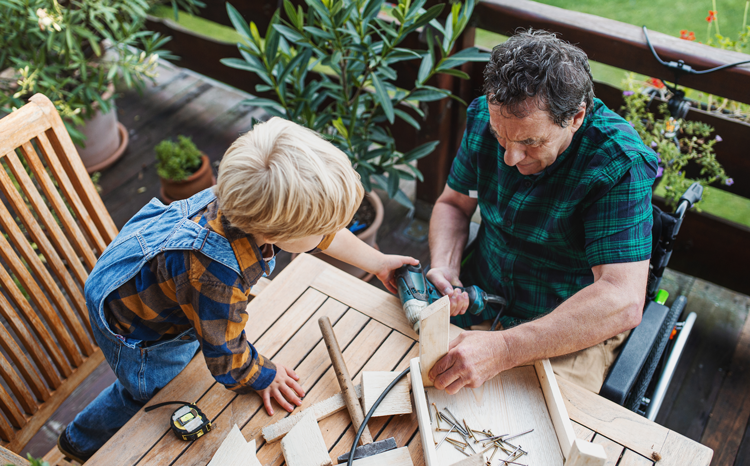 grandson and grandfather using power drill to make a bird house together