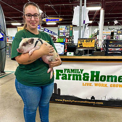 Employee holding baby a pig in store